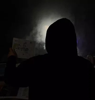 Silhouette einer Person im Kapuzenpulli im Dunkeln